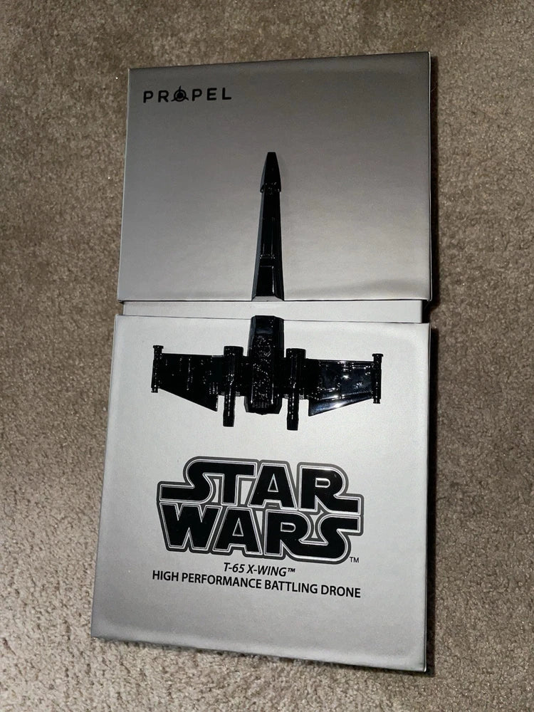 Open box of Propel Star Wars battle drone, showing black X-wing T-65 figure and logo
