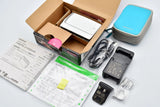 White compact digital camera kit with battery, charger, cables, manuals, and case