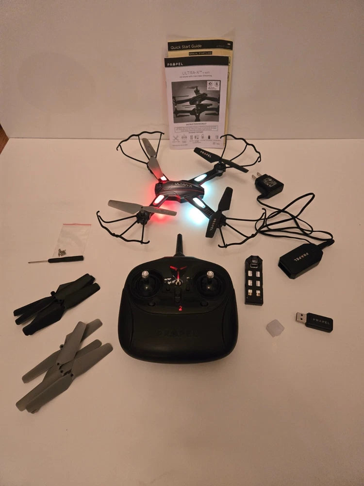 Black quadcopter RC drone with illuminated LEDs and remote controller, plus batteries and parts