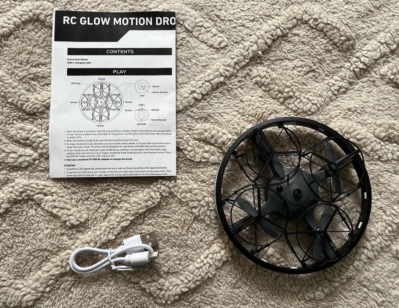 RC glow motion hover disc drone, black, with charging cable and instruction sheet