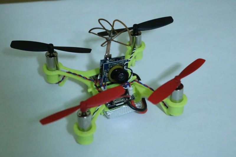 Micro FPV racing quadcopter drone with green arms and red propellers, front camera
