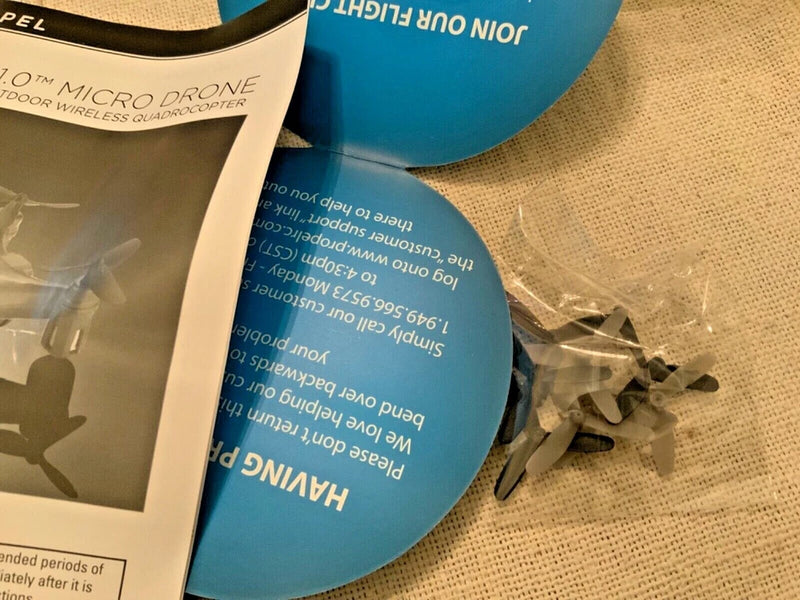 Micro drone instruction booklet with blue propeller part and spare plastic pieces