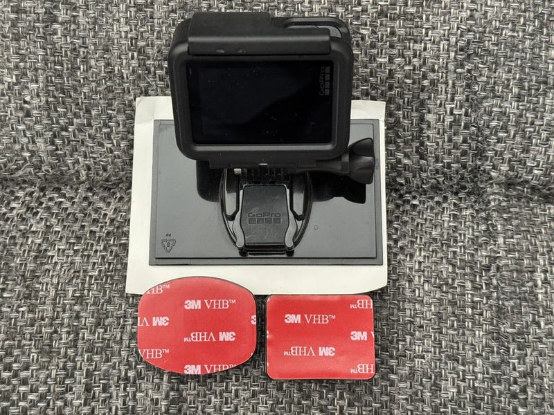Black action camera with front touchscreen display and mounting bracket