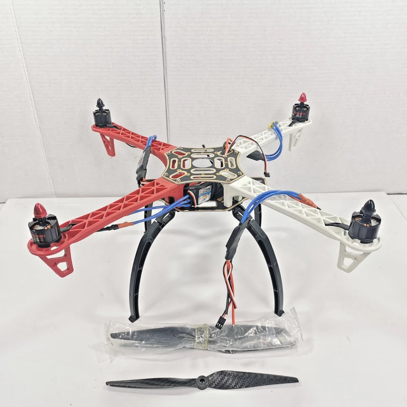 Carbon fiber quadcopter frame with four motors and wiring, red and white.