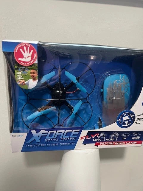 Hand-controlled quadcopter drone in blue retail box with visible propellers and controller
