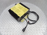 Battery charger assembly with yellow label, black finned housing, and cable connectors