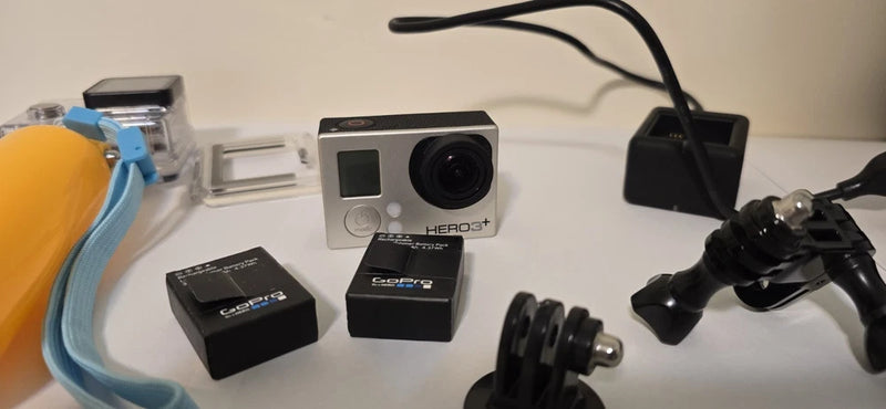 Silver action camera kit with front lens, two batteries, and mounting accessories