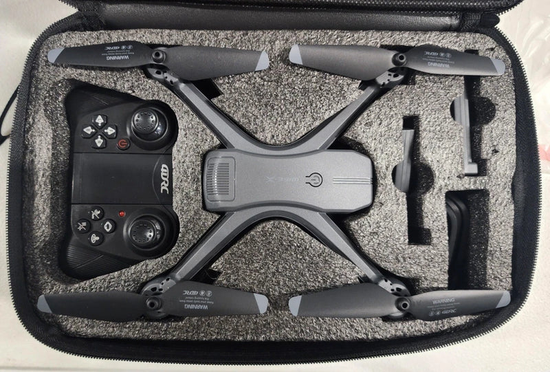 Quadcopter drone with gray arms, remote controller, and accessories in carry case