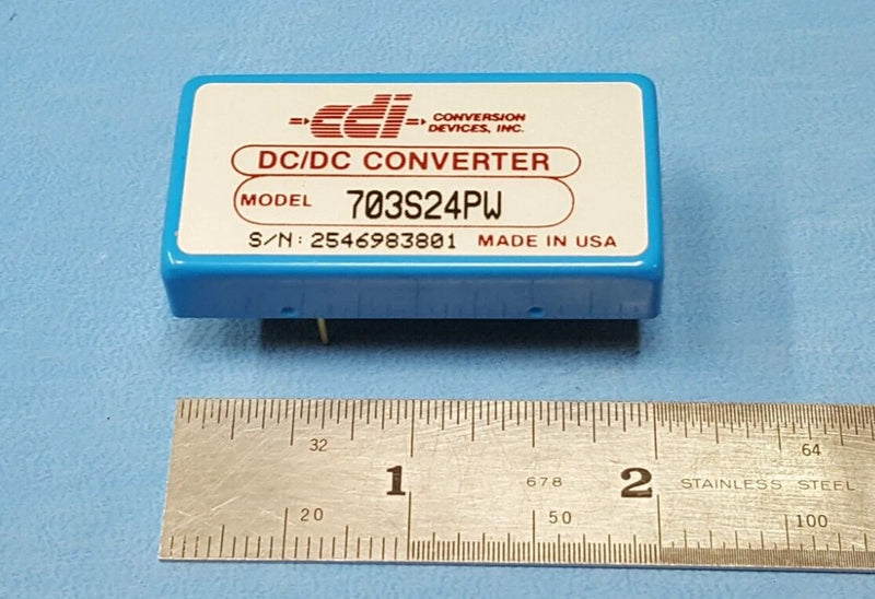 DC/DC converter module with label, model 703S24PW, made in USA, shown with ruler