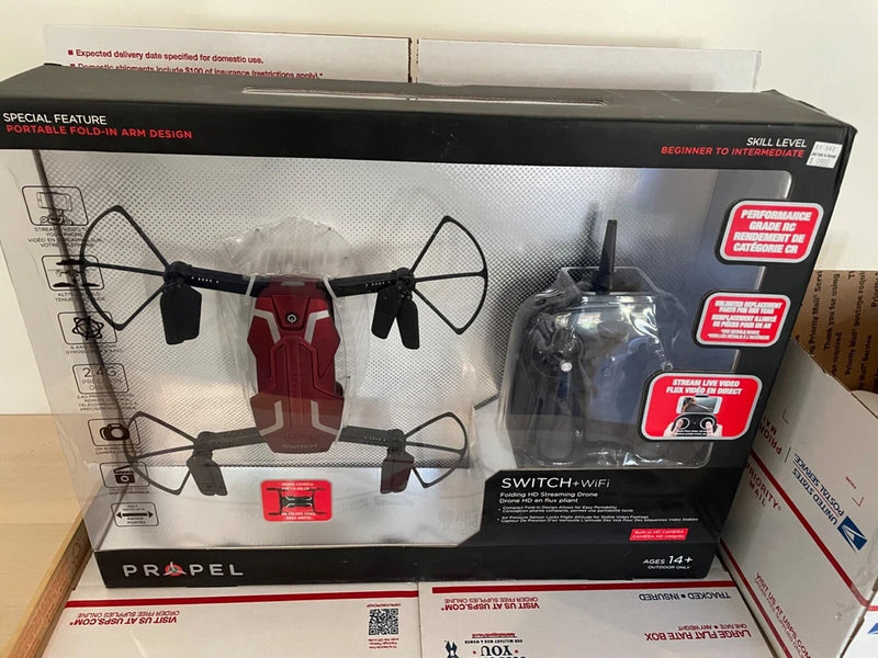 Black quadcopter drone with 4 propellers and remote in retail box packaging