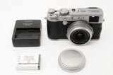 Black compact digital camera with silver lens and top controls; includes battery and cap