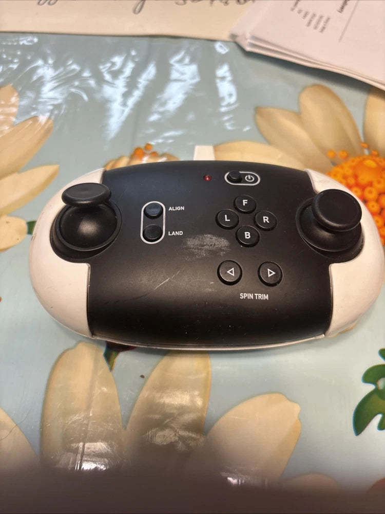Black drone remote controller with dual joysticks, buttons, and power switch
