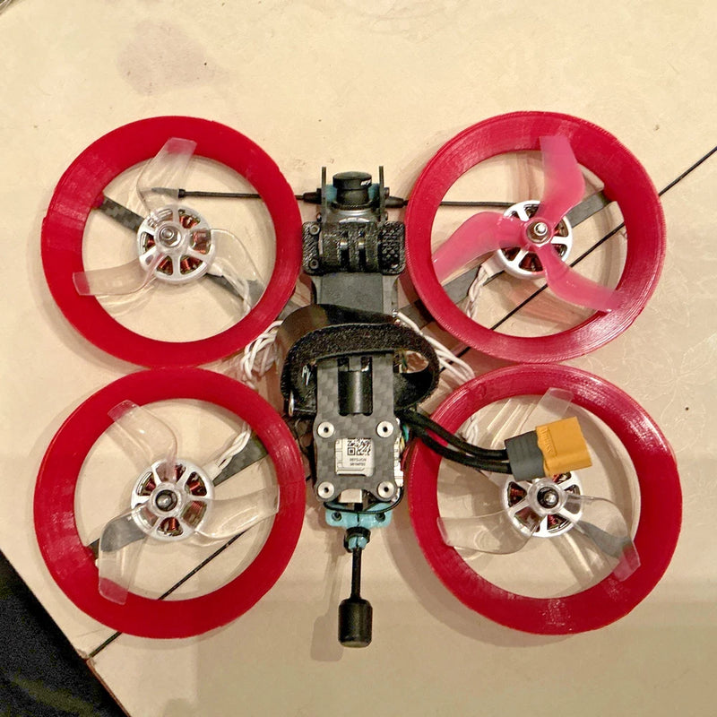Cinewhoop drone kit with four red ducted propellers and central flight controller