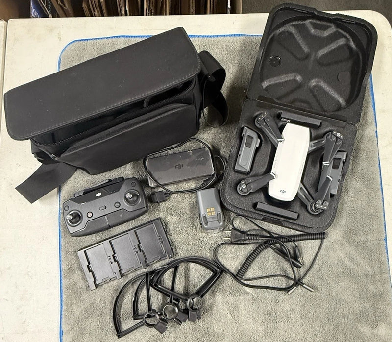 White quadcopter drone with controller, batteries, propellers, and case
