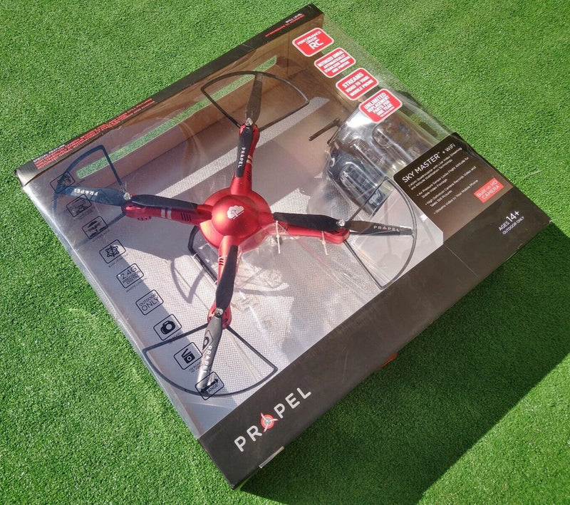 Red quadcopter drone with four propellers in clear retail box packaging