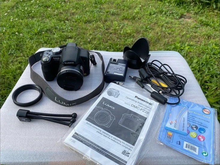 Digital camera bundle with strap, lens hood, cables, manuals, and software discs