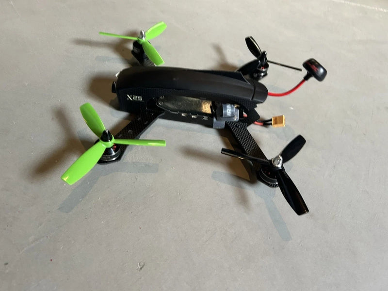 Black racing drone with green propellers and front camera module, used
