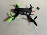 Black racing drone with green propellers and front camera module, used