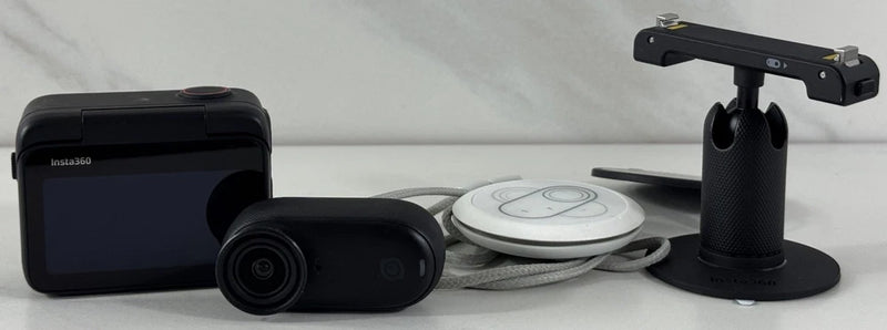 Midnight black tiny action camera with handheld stand and white accessory