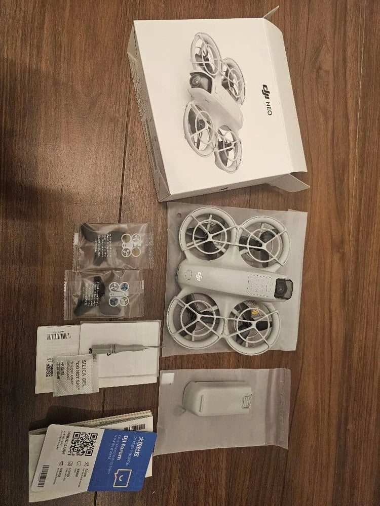 Small white quadcopter drone kit with propellers, box, and accessory paperwork