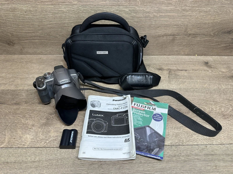Panasonic Lumix DMC-FZ28 digital camera with black case, strap, manuals, and battery