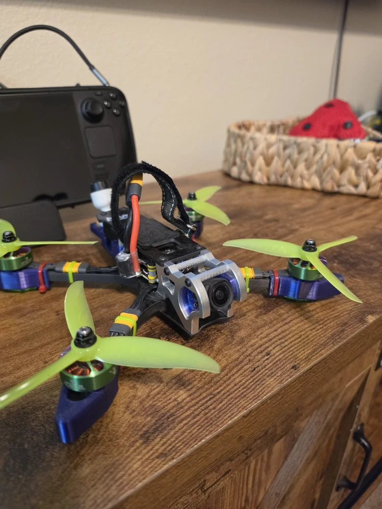 Small FPV quadcopter drone with green propellers and front camera module
