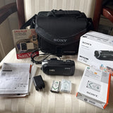 Black Sony Handycam HDR camcorder with lens cap, soft case, charger, and manuals