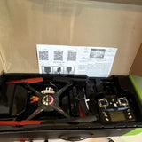Black quadcopter drone kit with orange arms, controller, and accessories in box