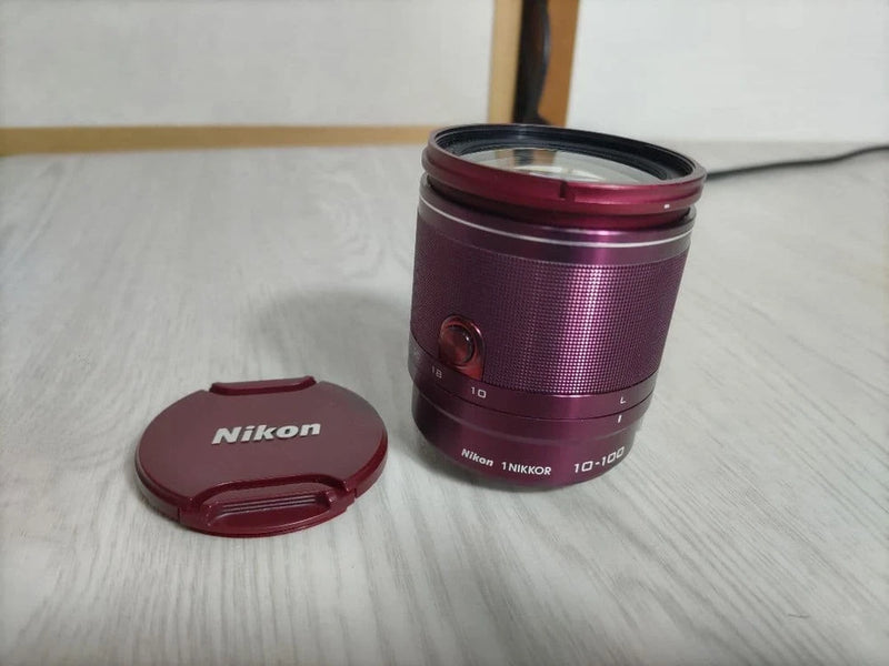 Nikon 10-100mm VR camera lens with front glass and maroon lens cap