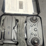 Gray folding quadcopter drone and remote controller, stored in carrying case