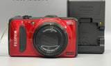 Red FUJIFILM FinePix digital camera with FUJINON lens and grey battery dock