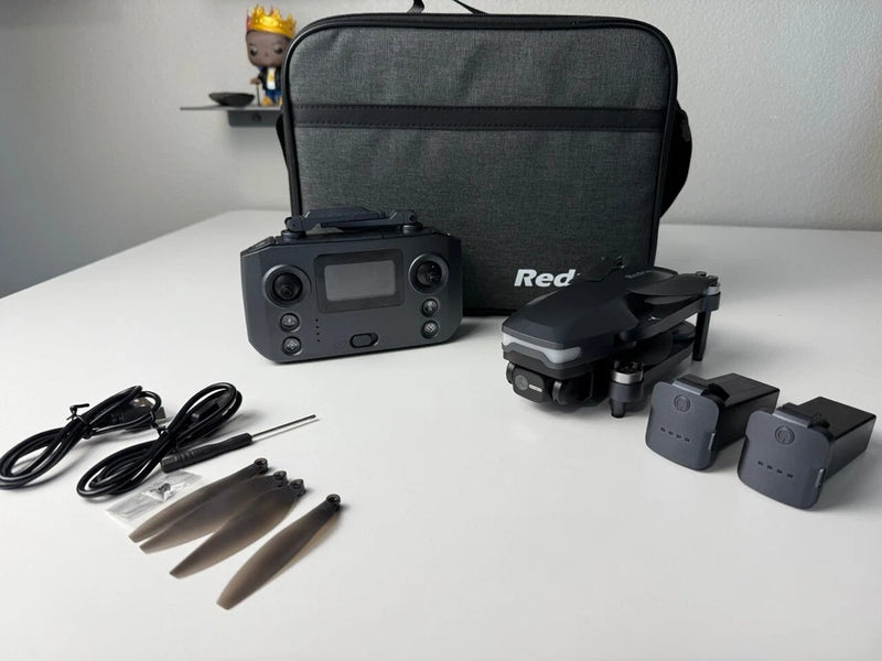 Gray quadcopter drone with camera, remote controller, propellers, and carrying case