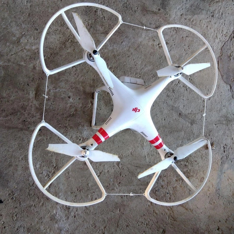 White quadcopter drone with four propellers and landing legs