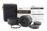 Black 30mm F1.4 camera lens with hood, filter, front cap, and carrying case