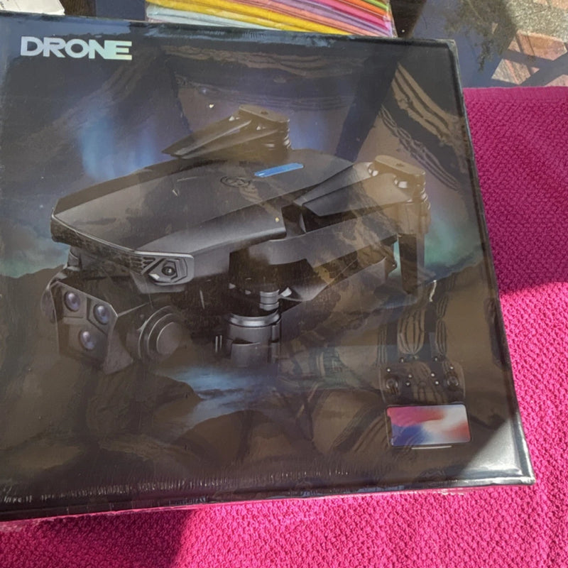 Black quadcopter toy with camera, shown in retail box front view