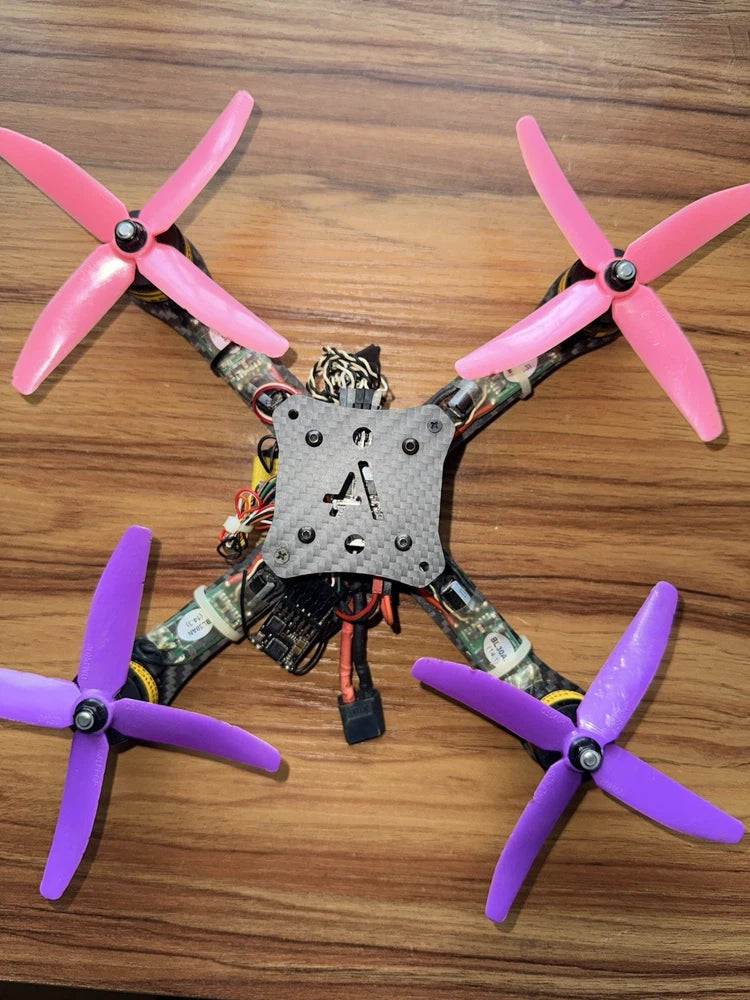 FPV quadcopter drone with four pink propellers and central circuit frame