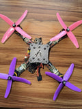FPV quadcopter drone with four pink propellers and central circuit frame