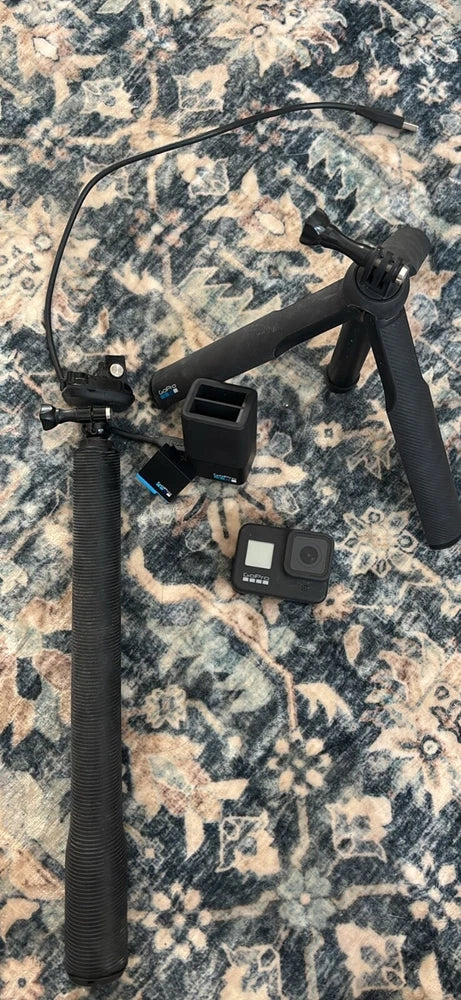 Black GoPro Hero 8 camera on handheld grip with accessories and battery