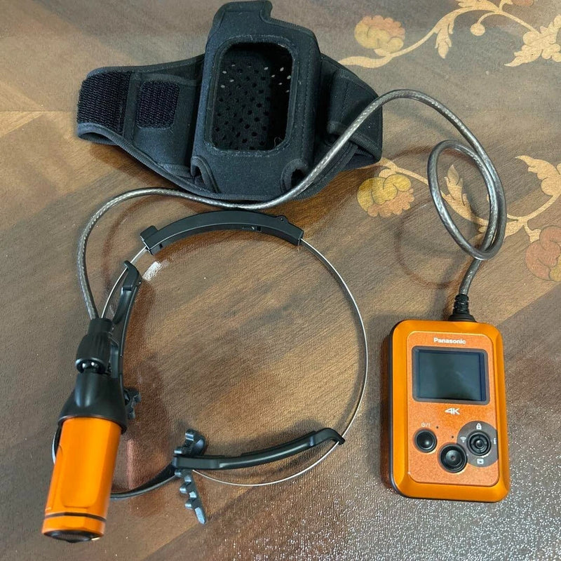 Orange Panasonic wearable 4K POV camera with chest mount, display, and connected cables