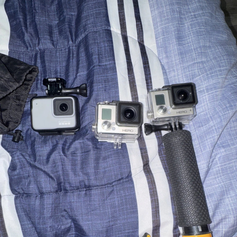 GoPro waterproof action cameras in clear housings with black lenses, mounted on grips
