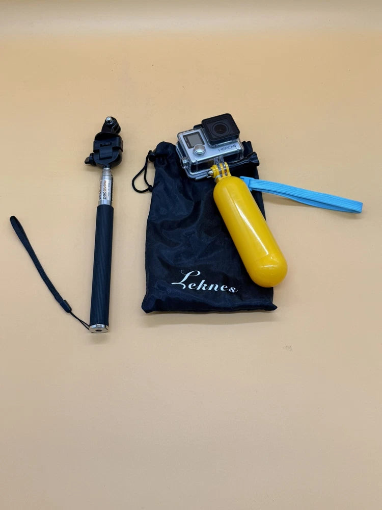 Action camera with waterproof housing on silver monopod, yellow handle and accessory bag