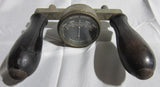 Vintage battery tester with two black rubber handles and round amp gauge dial