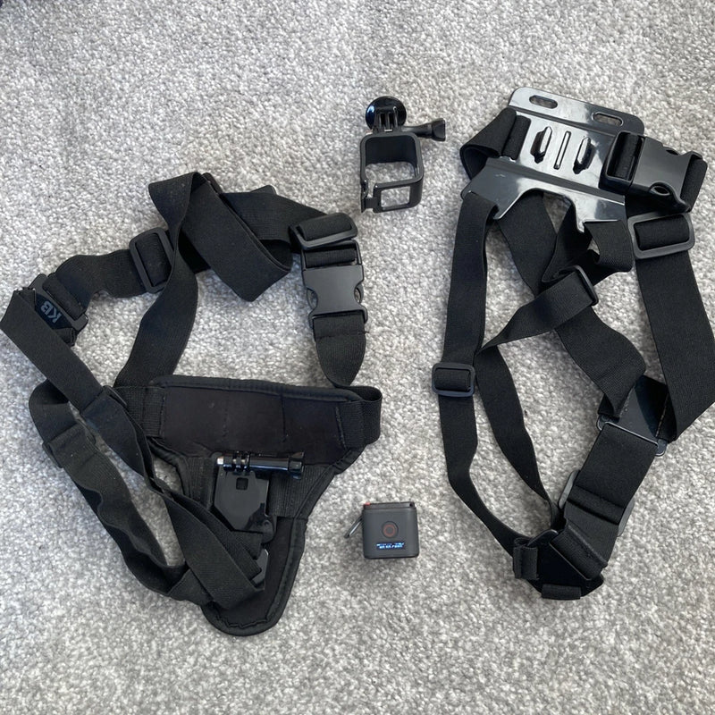 Black action camera chest mount harness with small action camera and accessory clip