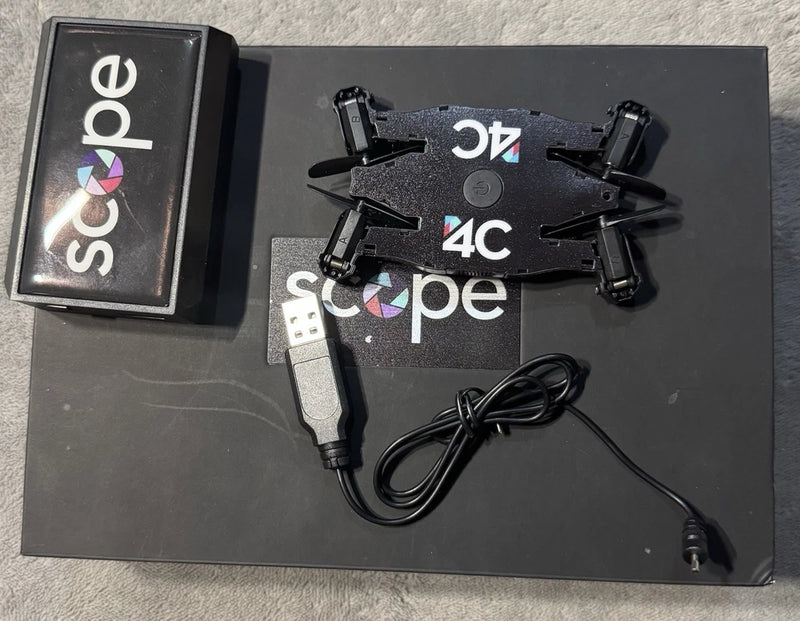 Black compact selfie drone with scope, USB charger cable and portable power case
