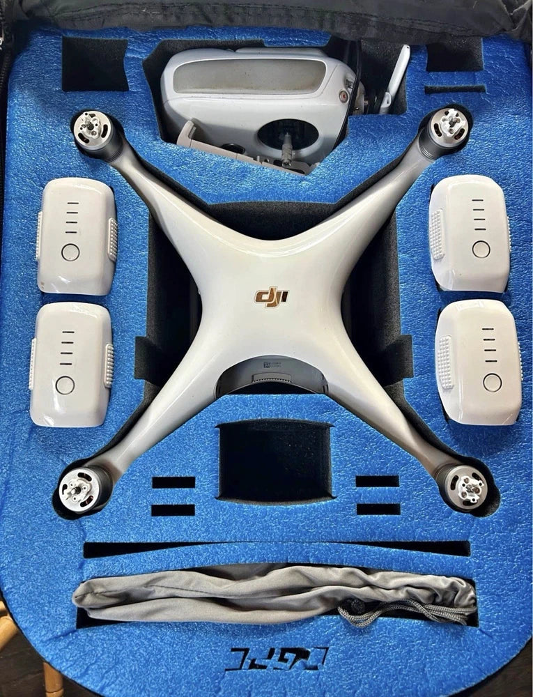 White quadcopter drone with four prop arms and controller accessories in foam case
