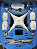 White quadcopter drone with four prop arms and controller accessories in foam case