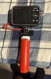 Kids mini camera with black screen and buttons, red grip handle on small tripod mount