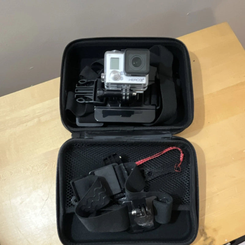 Black waterproof action camera with mounts in a hard case, open view