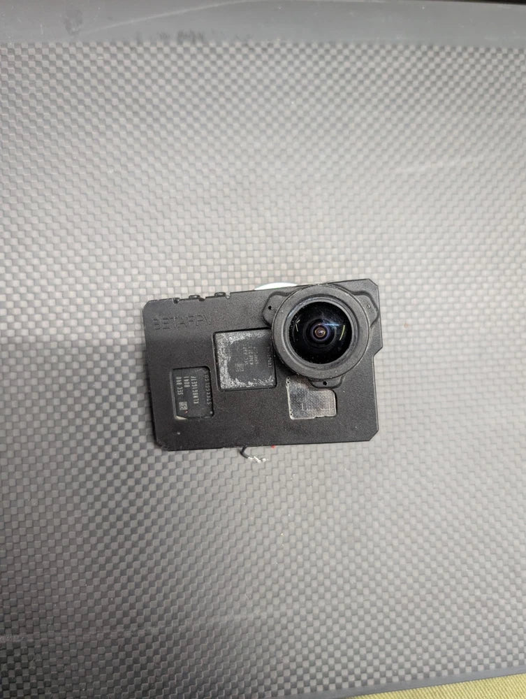 Silver action camera with circular lens and front display, rugged case design