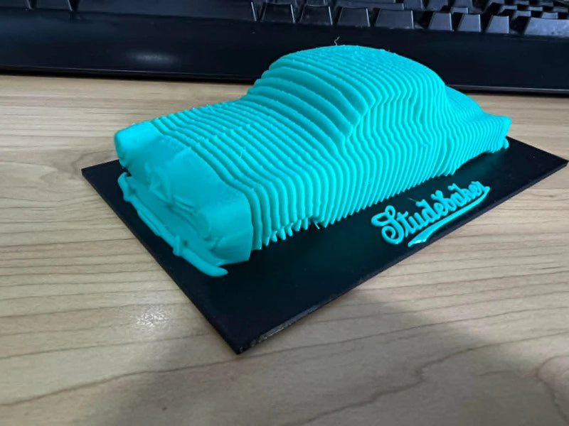 Blue layered car model cake on a black base with “Starlight” text